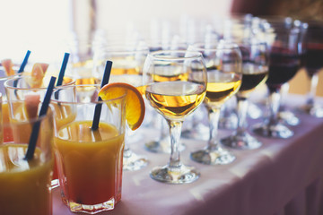 Beautiful row line of different colored alcohol cocktails on a party,  on decorated catering bouquet table
