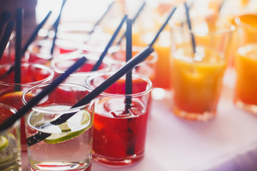 Beautiful row line of different colored alcohol cocktails on a party,  on decorated catering bouquet table
