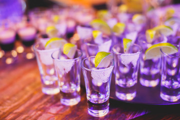 Beautiful row line of different colored alcohol cocktails on a party,  on decorated catering bouquet table
