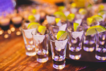 Beautiful row line of different colored alcohol cocktails on a party,  on decorated catering bouquet table
