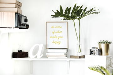 Design home interior with mock up poster frame , hourglass, vintage radio, succulent, camera and modern tropical leafs. Concept of shelf in scandi interior. 