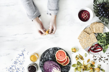 Woman in the kitchen and her healthy food eating selection: fruits, vegetables, super food, seeds,...