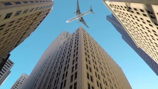 BOTTOM UP, CLOSE UP: Large commercial airplane flies low and close to tall skyscrapers. Breathtaking shot of aeroplane flying over high-rising buildings in business district of metropolitan city.