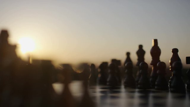 Close up of camera moving across a chess board at sunset, in slow motion