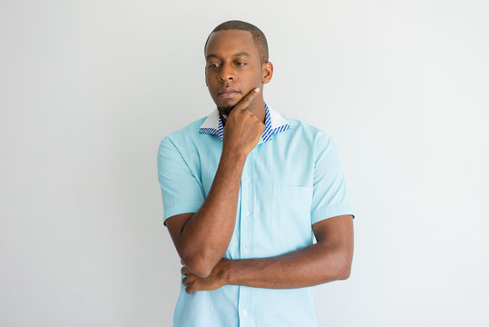 Introspective Handsome Young African Man Rubbing Chin And Looking Down. Pensive Guy Thinking Alone. Contemplation Concept