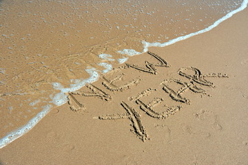 Happy new year written on sand at sunset. Happy New Year lettering on the beach. 