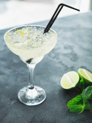 Mojito cocktail with lime in glass on a dark table