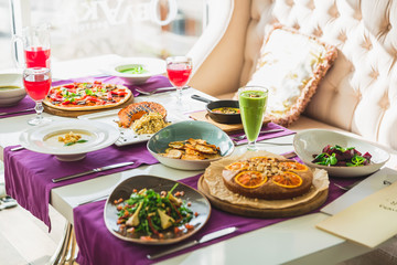 Table in restaurant with vegetarian dishes - pizza, salads, pie and fresh natural drinks.