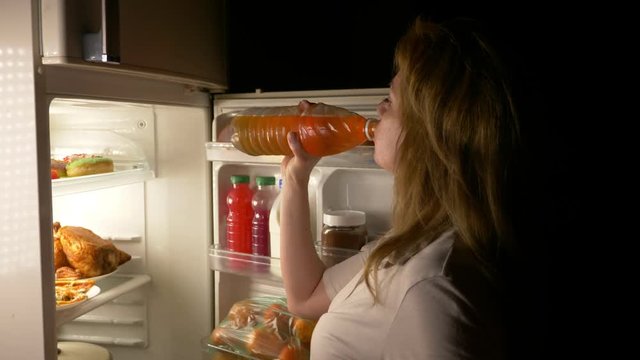 Woman opens the refrigerator at night. night hunger. diet. gluttony, 4k
