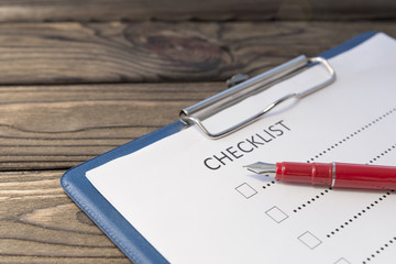 checklist, fountain pen on the background of a wooden table. business planning