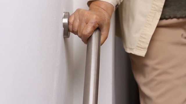 Elderly woman holding on handrail for safety walk steps