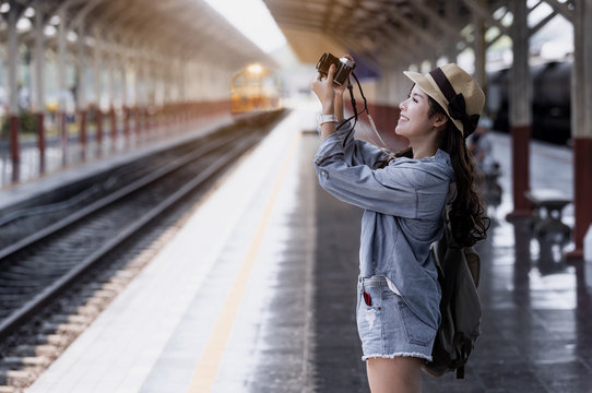 Young beautiful woman traveler with backpack holding vitage camera and taking photos