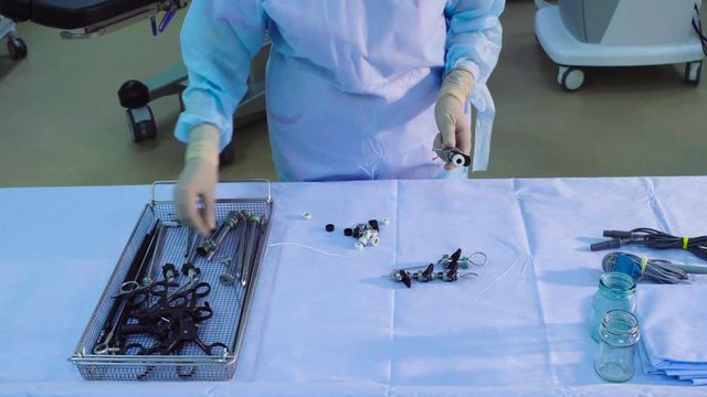 Time lapse. A surgical nurse picking up and putting on the table a sterile medical instruments for laparoscopic surgery