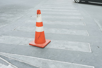 Traffic cone, with white and orange stripes on gray asphalt, copy space, Crosswalk