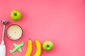 Homemade baby food. Cook puree with apple and banana with immersion blender. Pink background with...