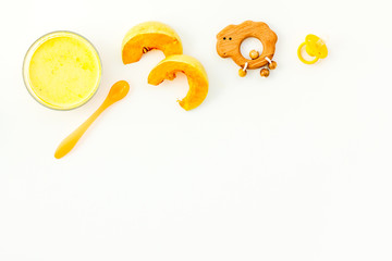 Healthy food for little baby. Puree with pumpkin near pacifier and toys on white background top view copy space