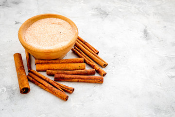 Cinnamon for cooking. Cinnamon sticks near bowl with sugar on grey background copy space