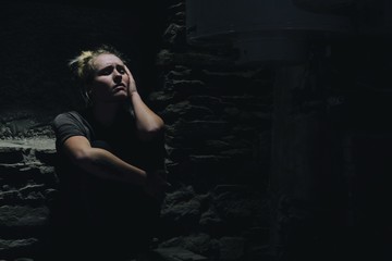 depressed anxious woman sitting in a dark corner of a basement