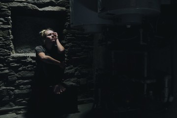 depressed anxious woman sitting in a dark corner of a basement
