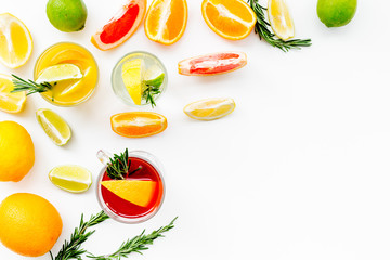 Concept of alcoholic cocktail with fruits. Glass with beverage near oranges, grapefruit, lime and rosemary on white background top view copy space