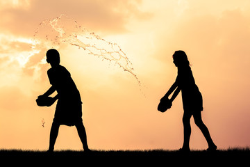 Children playing splash water on Songkran silhouette.