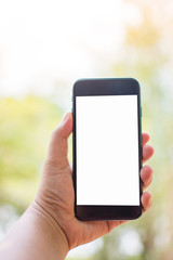 hand holding smart phone on nature background. Subject is blurred.