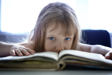 A little girl with blue eyes reads a book. Indigo children