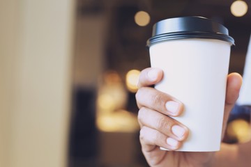 young man hand holding Paper cup of take away drinking coffee hot on cafe coffee shop.	