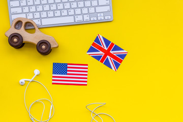 Teach english for a child. Funny english. British and american flags, computer keyboard, toy on yellow background top view copy space