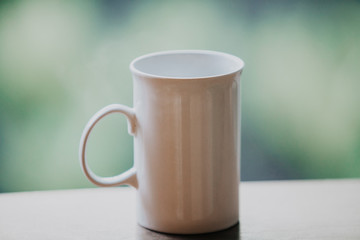 High white cup on green blurred background