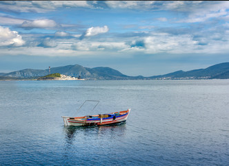 Fototapeta na wymiar small wooden traditional fishing boat against new gas factory, Pachi, Greece
