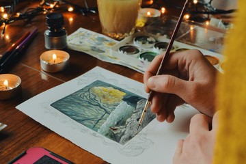 Fototapeta na wymiar woman painter artist painting a picture of a fantasy cave with watercolour