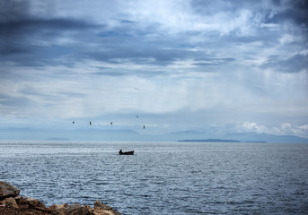 Fisherman in his  small boat under a dramatic blue sky