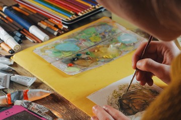 female artist painter woman paiting a watercolor picture of a bear, indoors, cozy wooden cabin