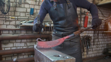 The blacksmith manually forging in the smithy