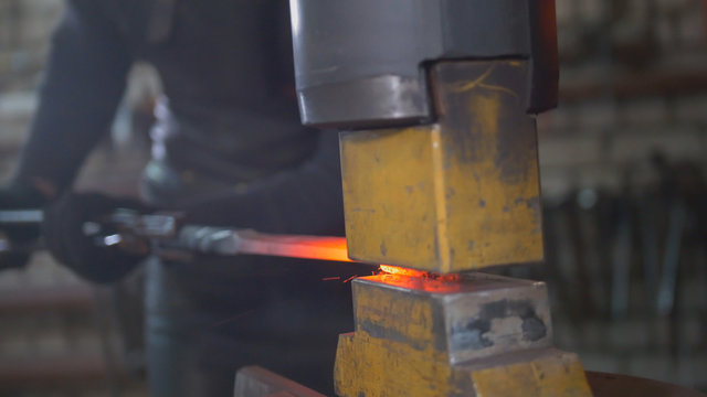 Molten metal is processed under pressure in the hands of a blacksmith