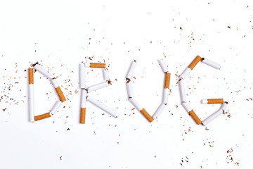Word Drug written with broken cigarettes on white background.