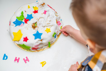 Little baby touches his birthday cake which lies on the table