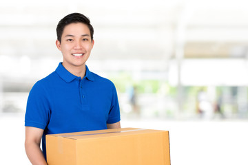 Friendly Asian delivery man  in blue polo shirt carrying parcel box