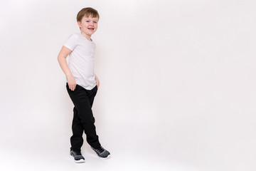 cute boy aged 6 years shows on a white background in different poses different emotions