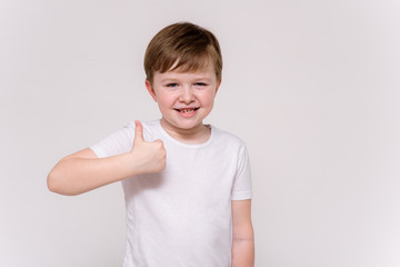 cute boy aged 6 years shows on a white background in different poses different emotions