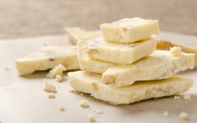 A pile of white chocolate with nuts on parchment paper. Sweet dessert.