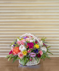 bouquet of flowers, colorful roses with green leaves standing in a wicker basket