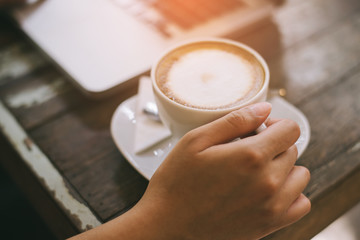 Woman typing on notebook computer in coffee shop