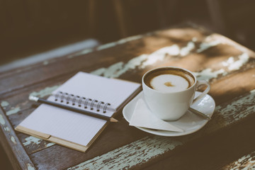 Notebook and coffee on wooden background