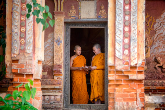 Two novices are standing reading books together in the temple. To study and share the knowledge of the education of priests in Thailand.