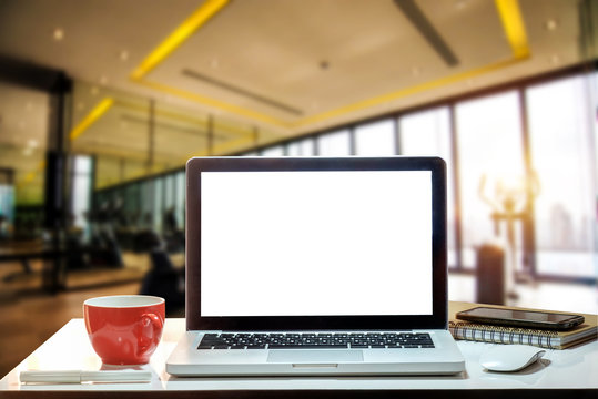 Front view of cup and laptop on table in Office in fitness gym in morning light
