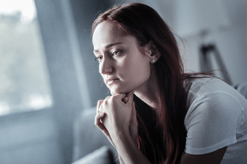 Stay strong. Pleasant sincere sad woman placing head on chin while thinking and feeling depression