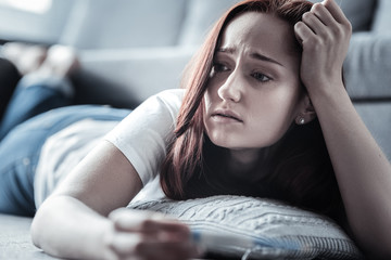 Mild fever. Melancholy unhappy worried woman touching hair while lying and feeling miserable