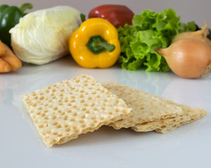 Slices of dietary bread on a background of fresh vegetables